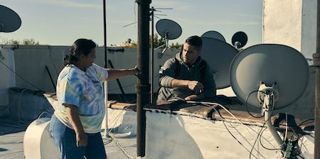 a man and a woman on the roof of a building between antennas