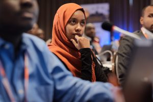 a woman in a headscarf sitting at an event listening