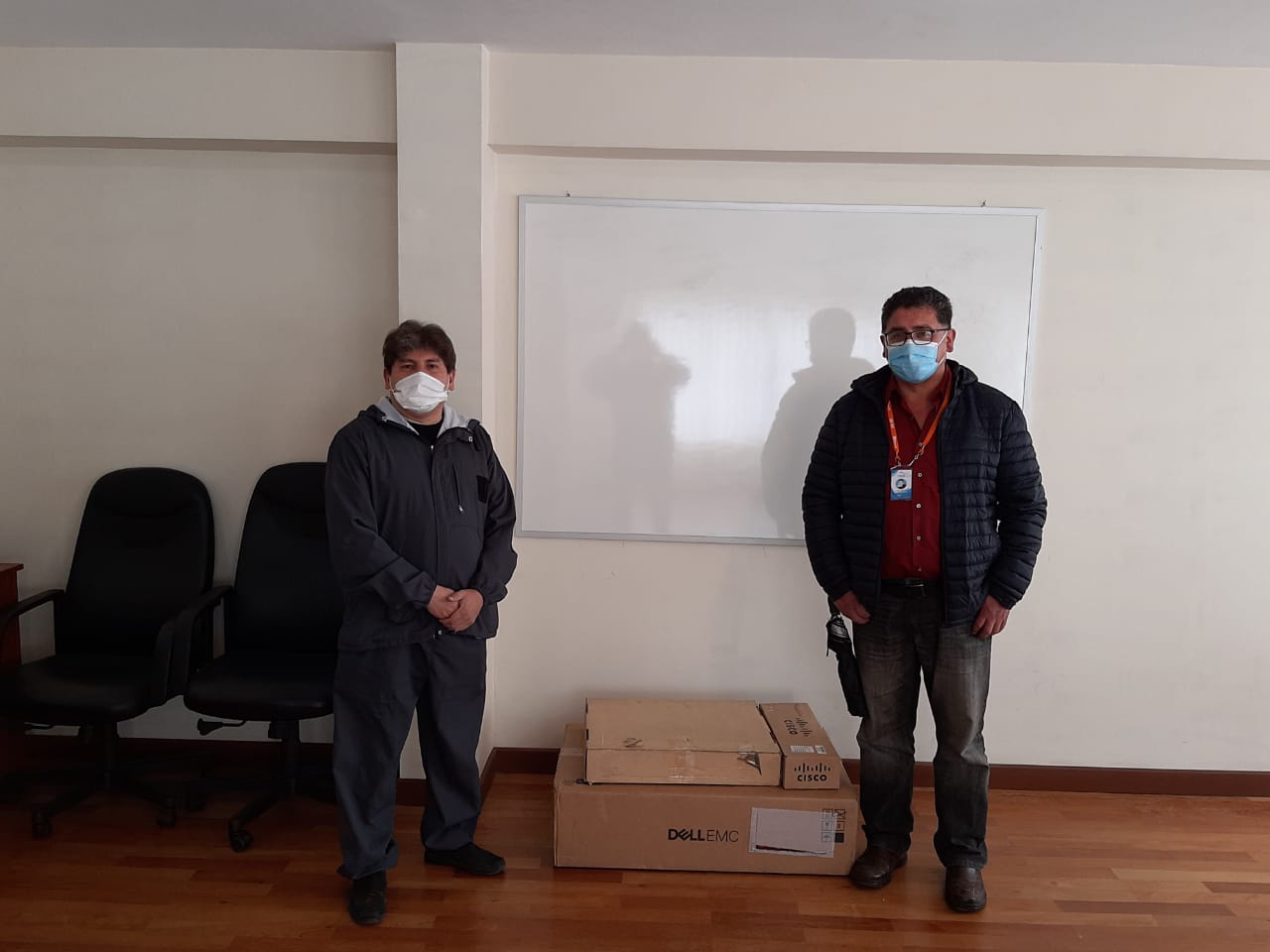 Two men with face masks standing between carton packages