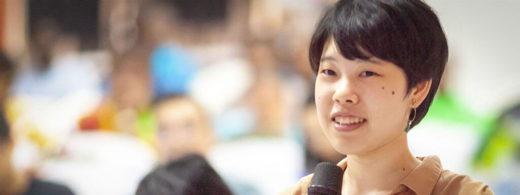 a girl holding a microphone speaking at an event