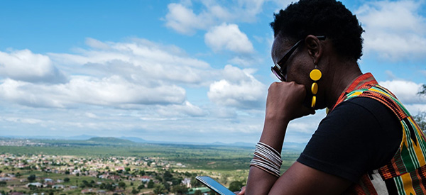 a woman looking at the phone sitting at the top of the hill