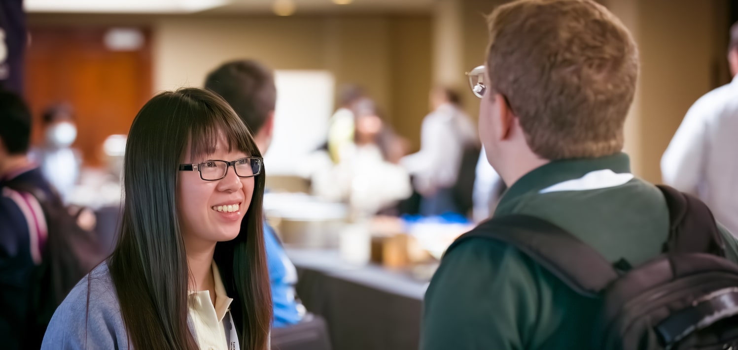 a young woman and a man talk at a conference